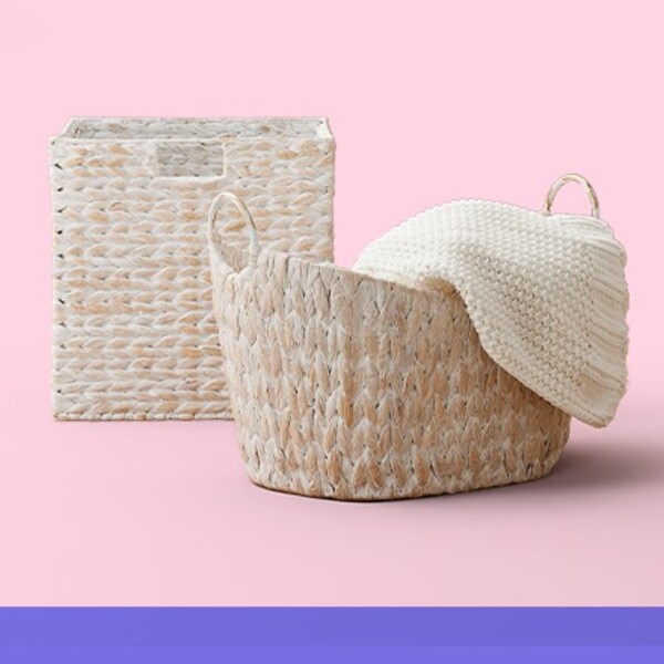 two white water hyacinth baskets on pink background
